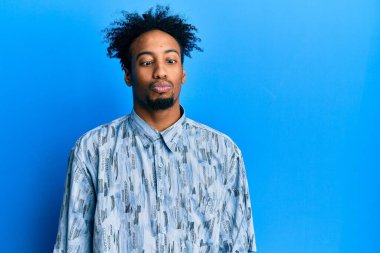 Sakallı, sıradan kıyafetler giyen, dudakları balıklı surat yapan, çılgın ve komik bir jest yapan Afrikalı genç bir Amerikalı. Komik ifade. 