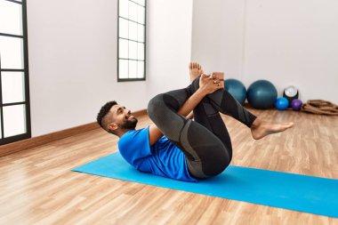 Yakışıklı İspanyol adam egzersiz yapıyor ve yoga minderinde geriniyor. Spor salonunda esneklik ve antrenman yapıyor.