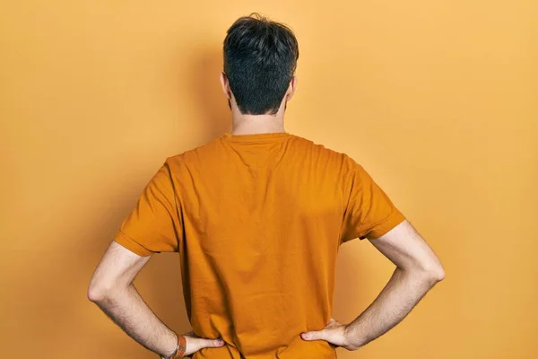 コーカシア人男で髭を生やしてカジュアルな黄色のTシャツを身に着けています後方に立って離れて腕で体 — ストック写真