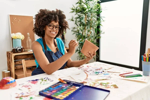 若いですアフリカ系アメリカ人女性笑顔自信に満ちた絵画粘土鍋でアートスタジオ — ストック写真