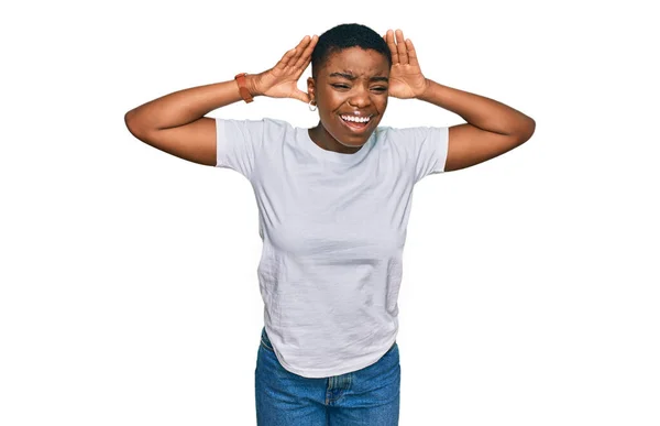 若いアフリカ系アメリカ人の女性は 耳のジェスチャーで両方の手を聞くしようとしてカジュアルな白いTシャツを着て ゴシップを好奇心 聴覚障害や聴覚障害 — ストック写真