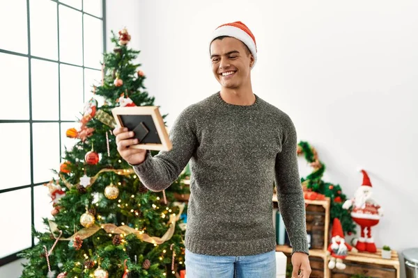 Joven Hombre Hispano Mirando Foto Pie Junto Árbol Navidad Casa — Foto de Stock