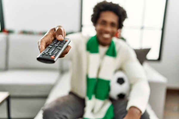 stock image Young african american hooligan man smiling happy supporting soccer team sitting on the sofa at home.