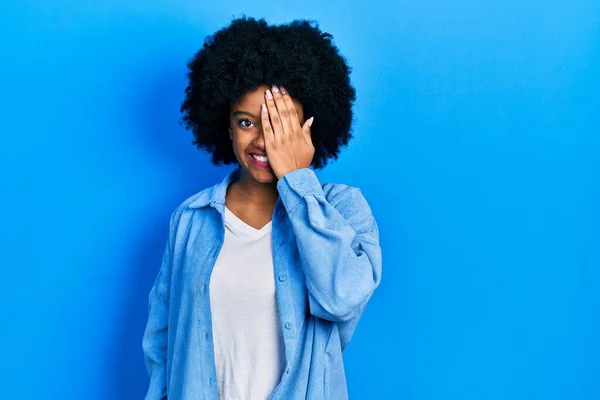 若いアフリカ系アメリカ人の女性は 手で片目を覆い 顔に自信を持って笑顔と驚きの感情を身に着けている — ストック写真