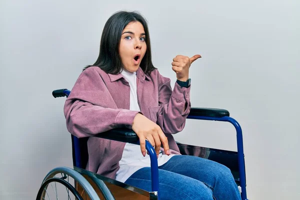 Jovem Morena Sentada Cadeira Rodas Surpreso Apontando Com Dedo Mão — Fotografia de Stock