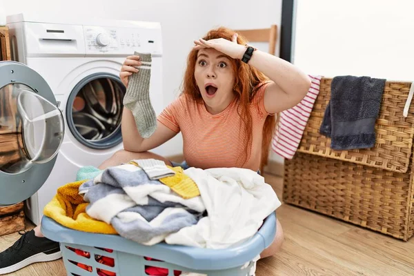 若い赤毛の女性は洗濯機に汚れた洗濯機を入れて非常に幸せと笑みを浮かべて遠くに手を頭の上に見て 検索の概念 — ストック写真