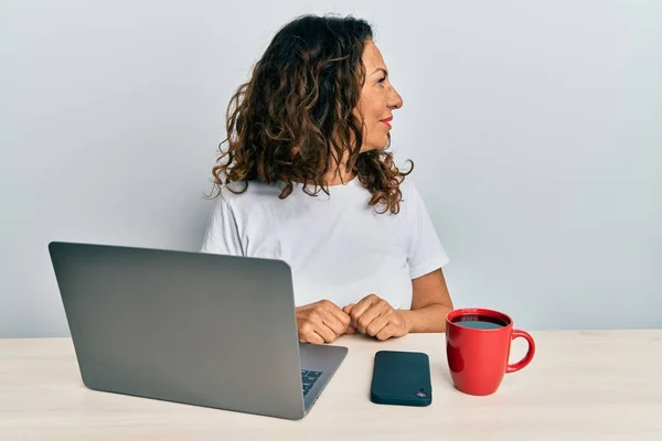 漂亮的中年女性在办公室工作时 用电脑笔记本电脑向旁边看去 带着自信的微笑放松自己的姿态 — 图库照片
