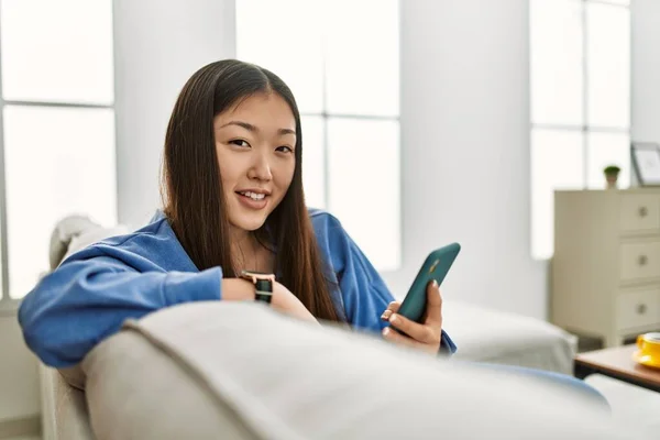 Ung Kinesisk Flicka Med Hjälp Smartphone Sitter Soffan Hemma — Stockfoto