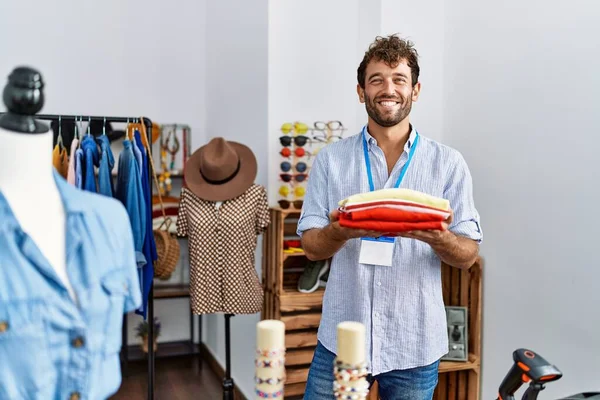 Young Hispanic Shopkeeper Man Smiling Happy Holding Stack Sweater Clothing — Stock Photo, Image