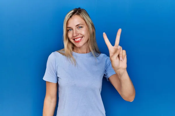 Vacker Blond Kvinna Bär Casual Skjorta Över Blå Bakgrund Ler — Stockfoto