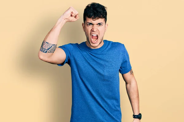 Joven Hombre Hispano Vistiendo Camiseta Casual Enojado Loco Levantando Puño —  Fotos de Stock