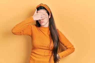 Genç esmer genç, gündelik sarı kazak giyiyor, gözleri elle örtüyor, ciddi ve üzgün görünüyor. Görme, saklama ve reddetme konsepti 