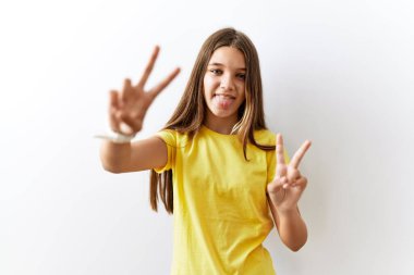 Genç esmer ergen, izole edilmiş arka planda yan yana durur ve iki elini de zafer işareti yaparak parmaklarını göstererek gülümserdi. İki numara.. 