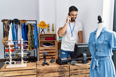 Genç Arap esnaf giyim mağazasında çalışan akıllı telefondan konuşuyor.