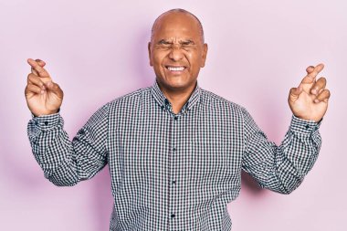 Orta yaşlı, sıradan kıyafetler giyen, umut ve gözlerin kapalı gülümseyerek el sallayan Latin bir adam. Şans ve batıl inançlar. 