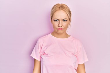 Sıradan pembe tişörtler giyen genç sarışın kadın depresif ve endişeli, sinirli ve korkmuş bir şekilde ağlıyor. hüzünlü ifade. 