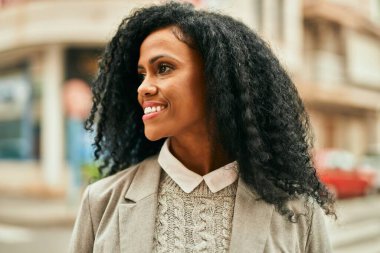 Orta yaşlı Afro-Amerikan iş kadını şehirde mutlu bir şekilde dikilirken gülümsüyor.