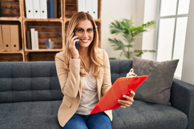 Psikoloji merkezindeki akıllı telefondan konuşan genç sarışın kadın psikolog.
