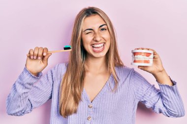 Güzel İspanyol kadın takma diş ve diş fırçasıyla kameraya bakıyor. Seksi bir ifadeyle, neşeli ve mutlu bir yüzle.. 