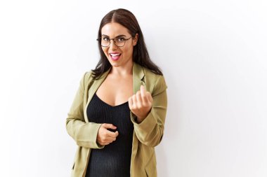 Genç esmer kadın izole edilmiş arka planda duruyor. Buraya el kol hareketi yaparak mutlu bir şekilde karşılamaya ve gülümsemeye davet ediyor. 