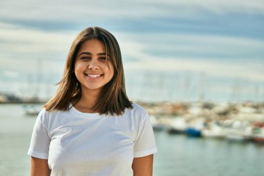 Plajda mutlu mutlu gülümseyen genç Latin kız..