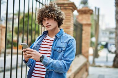 Genç İspanyol adam şehirde akıllı telefon kullanıyor.