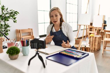 Beyaz kadın resim atölyesinde resim dersi veriyor.