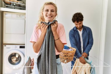 Genç çift çamaşır yıkarken mutlu gülümsüyor. Evde temiz giysiler kokan bir kadın..