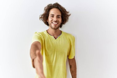 Soyutlanmış arka planda duran genç İspanyol adam dostça bir selamlama ve hoş geldin hediyesi olarak el sıkışmayı sunuyor. başarılı iş. 