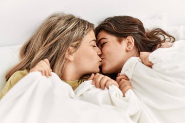 Genç ve güzel bir çift yatakta uzanıyor ve evde battaniyeyle sarılıyorlar..