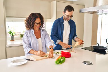 Orta yaşlı İspanyol çift mutfakta kendine güvenen yemekler pişiriyor.