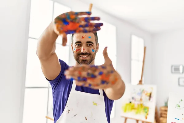 Młody Hiszpan Uśmiecha Się Pewnie Pokazując Pomalowane Dłonie Pracowni Artystycznej — Zdjęcie stockowe