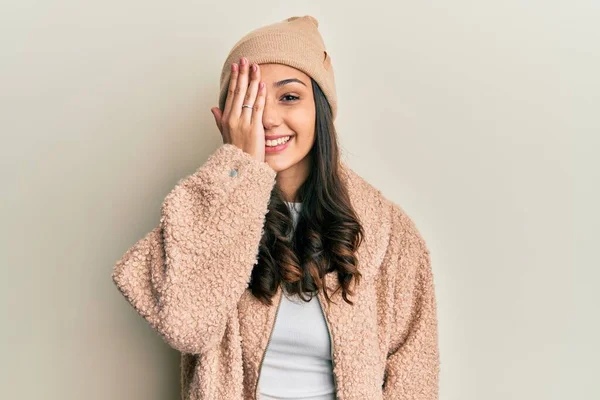 年轻的惊慌失措的女人 身穿羊毛衫 头戴冬帽 一只眼睛蒙着 脸上带着自信的微笑 感情令人惊讶 — 图库照片