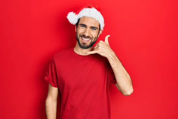 Νεαρός Ισπανός Που Φοράει Χριστουγεννιάτικο Καπέλο Χαμογελώντας Κάνει Τηλεφωνική Χειρονομία — Φωτογραφία Αρχείου