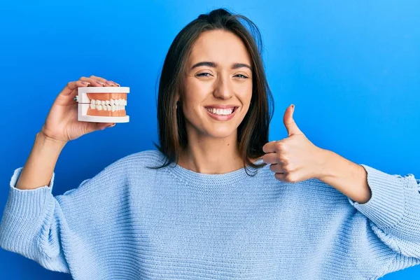 Menina Hispânica Jovem Segurando Dentadura Sorrindo Feliz Positivo Polegar Para — Fotografia de Stock