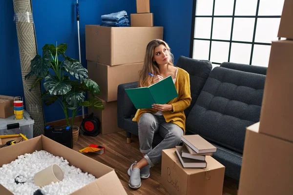 Joven Mujer Rubia Sentada Sofá Escribiendo Libro Casa Nueva — Foto de Stock