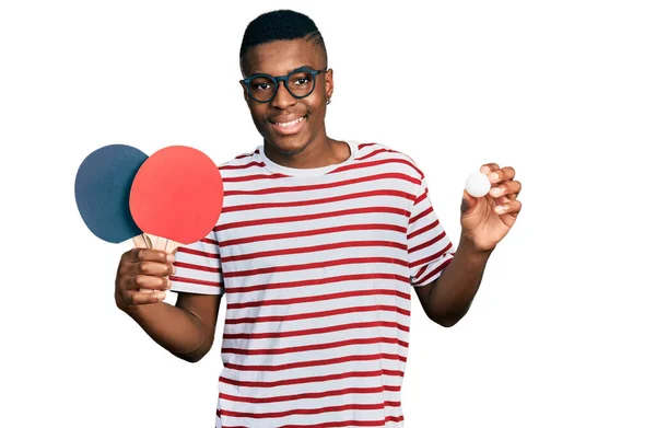年轻的非洲裔美国人 手里拿着红乒乓球球拍和球 脸上挂着快乐而沉着的笑容 显示牙齿 — 图库照片