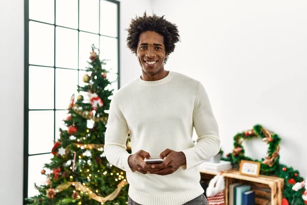 Joven Afroamericano Uisng Hombre Teléfono Inteligente Pie Junto Árbol Navidad — Foto de Stock