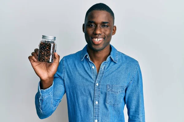 Joven Hombre Afroamericano Sosteniendo Frasco Con Granos Café Mirando Positiva — Foto de Stock