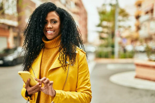 アフリカ系アメリカ人の中年女性が市内のスマートフォンを使って笑顔で幸せ — ストック写真