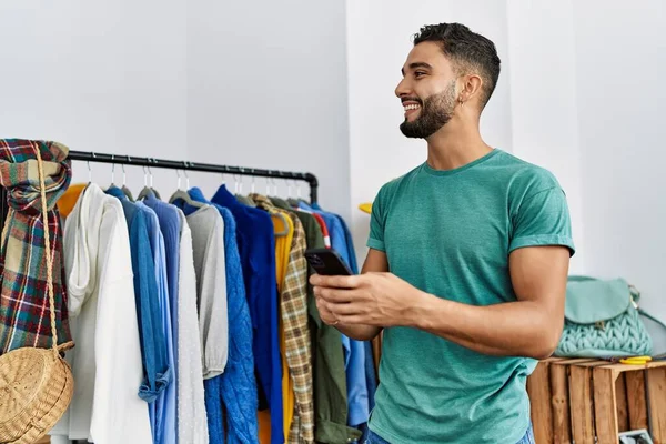 Giovane Arabo Uomo Cliente Utilizzando Smartphone Piedi Appendiabiti Negozio Abbigliamento — Foto Stock