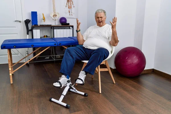 Homem Caucasiano Sênior Clínica Fisioterapia Usando Pedal Exercitador Celebrando Louco — Fotografia de Stock