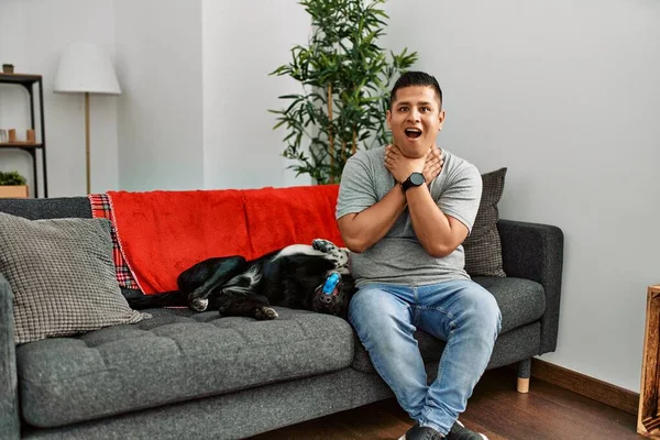 Jovem Latino Homem Cão Sentado Sofá Casa Gritando Sufocar Porque — Fotografia de Stock