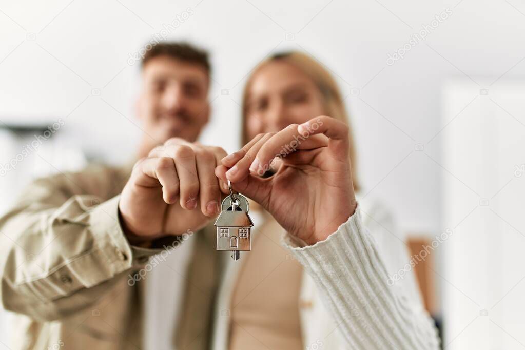 Young caucasian couple smiling happy holding key of new home.