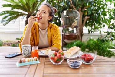Genç İspanyol kız kahvaltı yapıyor terasta masada oturuyor..