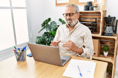 Kıdemli, gri saçlı, gülümseyen bir adam. Ofiste video görüşmesi yaptığından emin.