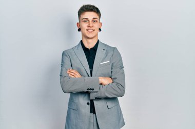 Kulakları genişlemiş, iş ceketi giymiş, kollarını kavuşturup kameraya gülümseyen beyaz bir çocuk. pozitif kişi. 