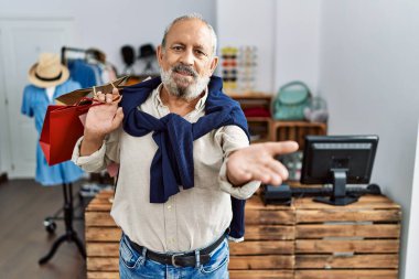Yakışıklı son sınıf öğrencisi butik dükkanında alışveriş poşetleri tutuyor. Gülümsüyor, yardım eli uzatıyor ve kabul ediyor.. 