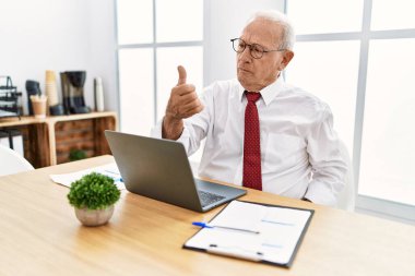 Ofiste çalışan son sınıf öğrencisi bilgisayar kullanıyor. Gururlu görünüyor, gülümsüyor. Kenarda baş parmak hareketi yapıyor. 