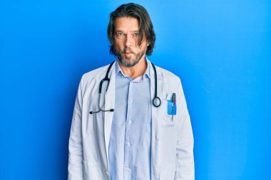 Doktor üniforması ve steteskop giyen orta yaşlı yakışıklı adam dudaklarıyla balık suratı yapıyor, çılgınca ve komik bir jest. Komik ifade. 